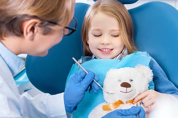 Niña en una revisión dental infantil con profesional sanitario